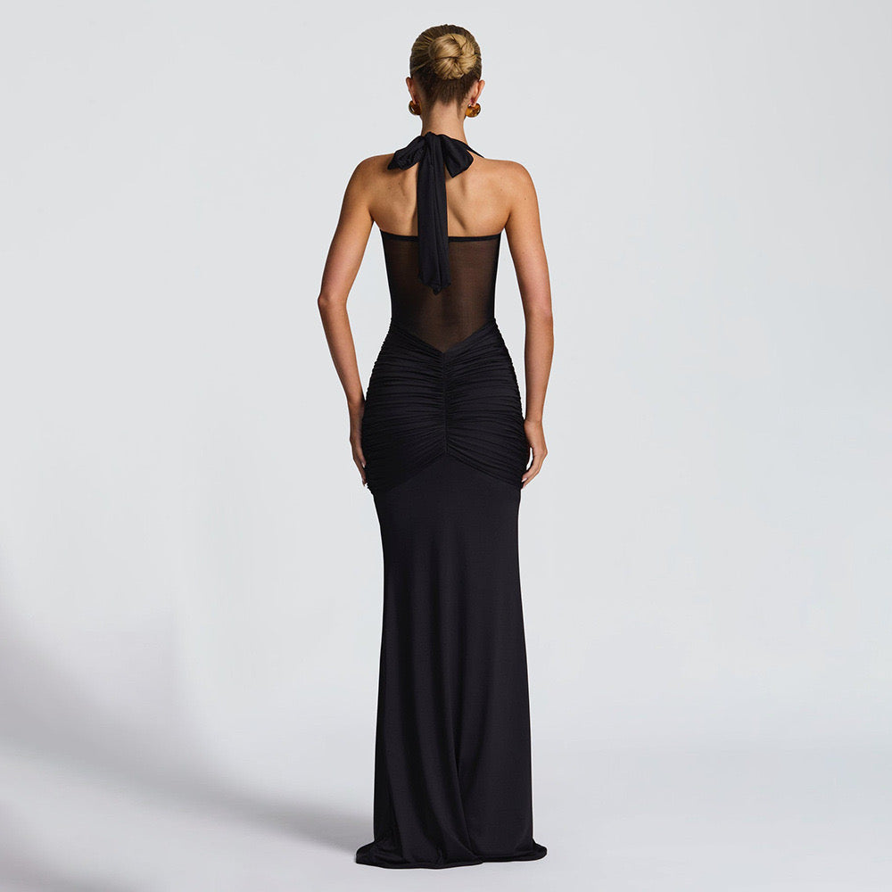 black evening gown with a halter neckline that ties at the back. The dress features a sheer mesh panel across the upper front torso